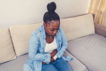 Woman in painful expression holding hands against belly suffering menstrual period pain, lying sad...