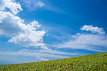 Green grass field on hills with blue sky and white clouds. nature landscape background. green grass field and bright blue sky