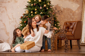 Family - mother and three children, happy together at home celebrating Christmas at a decorated Christmas tree