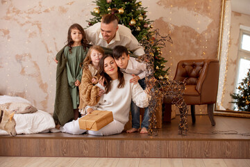 Family - father, mother and three children, happy together at home celebrating Christmas at a decorated Christmas tree