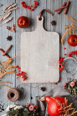 Thanksgiving decorations. Orange Hokkaido pumpkins, rowan berry, apples, cinnamon and Autumn decorations on old wood. Flat lay, top view with copy-space on wood cutting board.