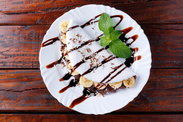 homemade tapioca or beiju stuffed with banana and chocolate on white plate over rustic wooden table