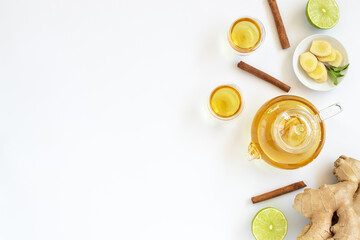 Top view of a cup of tea with ginger root, lime, cinnamon and teapot on white background. Health drink concept.