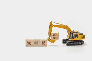 Concept Happy new year 2023,Crawler excavator with bucket lift up that is installing the numbers three on white backgrounds