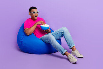 Full body photo of crazy astonished person sit cozy bag hold popcorn plate isolated on violet color...