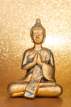 golden buddha in front of a gold glittering background