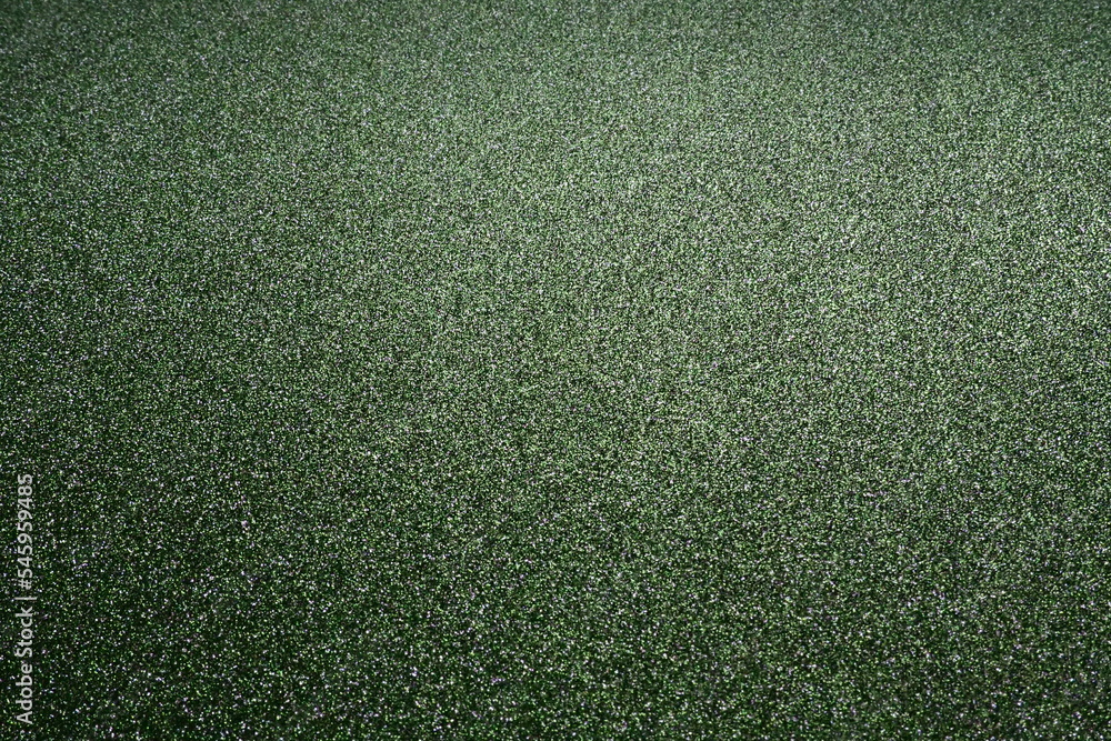Poster deep grassy green. texture of rough paper or cardboard. defocused bokeh sparkles and shine on the fo