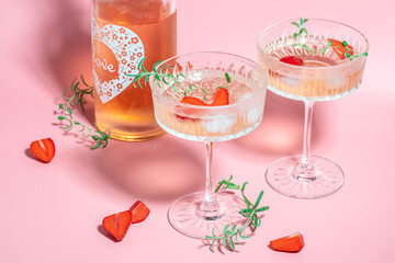 drink cocktail with ice in a glass on pink background. refreshing fruit cocktail or punch with wine champagne, strawberries, ice and rosemary