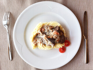 A plate of delicious potatoes and baked meat. top view of the serving