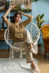 Young attractive woman chilling at home in comfortable hanging chair. Natural beauty of sensual...