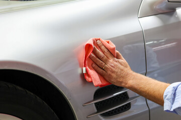 A man cleaning car with microfiber cloth, car detailing or valeting concept. 