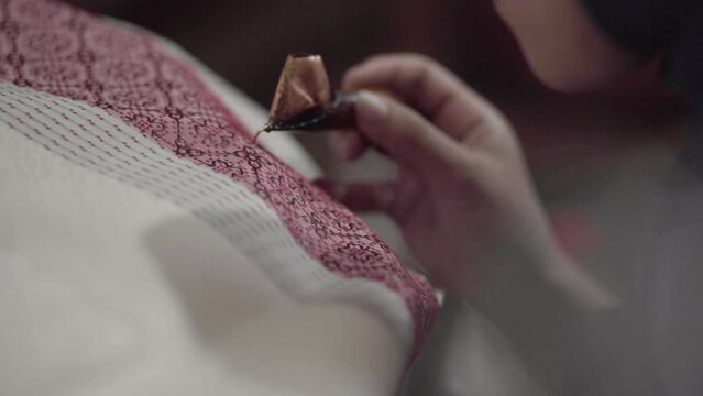 Female hand holding canting for making of batik tulis. Indonesian Batik