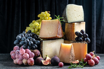 Assortment of different cheese types with grapes and figs. Cheese background. traditional pieces of Spanish, French, Italy cheese