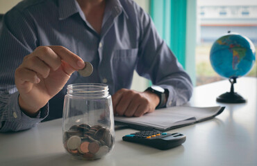 Retirement planning or investment accounting business concept finance insurance tax. Businessman person holding saving coin money in jar and calculator at desk.