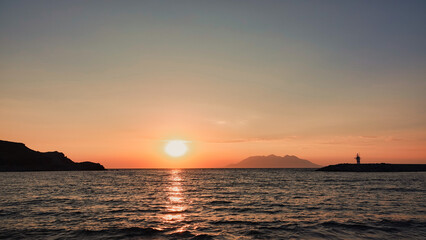 Sea port view, lighthouse, mountains and the opposite island of Samothrace in Gökçeada, Imbros Island at sunset