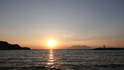 Sea port view, lighthouse, mountains and the opposite island of Samothrace in G&ouml;k&ccedil;eada, Imbros Island at sunset