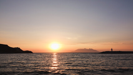 Sea port view, lighthouse, mountains and the opposite island of Samothrace in Gökçeada, Imbros Island at sunset