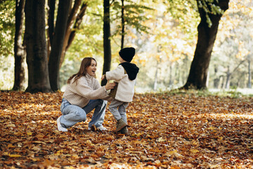 Fototapeta premium Mother with her little son walking in autumnal park