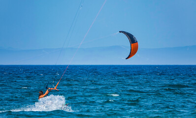 Professional Kite Surfer in action on Waves in sea. Kitesurf makes slalom on the waves