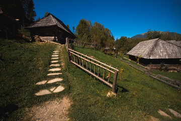 Fototapeta na wymiar Old Ukrainian village in the Carpathian mountains. A wooden staircase leads to the courtyard of old huts in the forest.