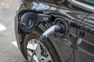 Close up on a cable plugged to an electric car charging at a charging station