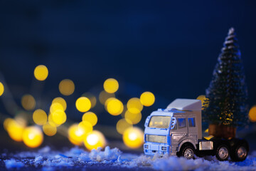Toy truck transports Christmas tree, festive background, bokeh garlands