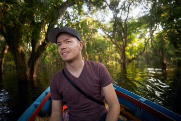 Man on boat exploring forest on lake near Siem Reap in Cambodia..
