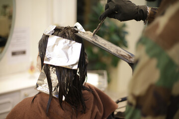 女性の髪に薬剤を塗布する男性美容師