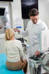 physician in white coat adjusting ultrasound machine while doing diagnostics of middle aged woman.