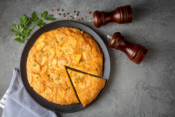 Spanish omelette with potatoes, typical spanish cuisine on gray concrete floor. Tortilla Espanola....