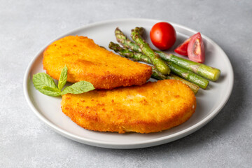 Chicken schnitzel with sauce, fried potatoes and lemon in a plate