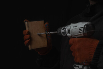 Hand holds cordless electric screwdriver with bit for screws and drilling isolated on black background