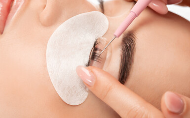 Make-up artist makes the procedure of lamination and dyeing of eyelashes to a beautiful woman in a...