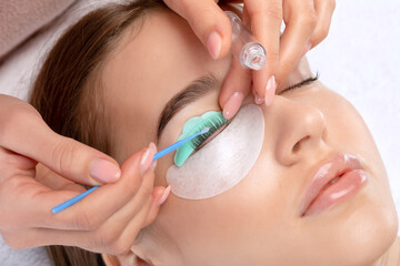 Make-up artist makes the procedure of lamination and dyeing of eyelashes to a beautiful woman in a...