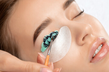 Make-up artist makes the procedure of lamination and dyeing of eyelashes to a beautiful woman in a...