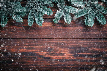 Christmas fir tree branches, Christmas balls, gift box, wooden snowflakes and stars on old brawn wooden background for your xmas greetings. Top view with copy space. Christmas greeting card.