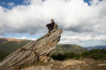 a young woman with a dog on top of a stone mountain