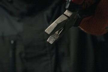 man's hand holding a black and red wire cutter plier open ready to cut form