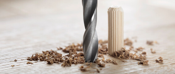 drill bit makes hole in wooden oak board for wooden dowel.