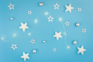 Fototapeta na wymiar Blue Christmas background with garland and decorative stars, flat lay.