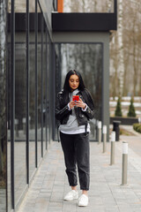 Obraz premium Beautiful caucasian woman with long dark hair talking by phone with friend while standing on street