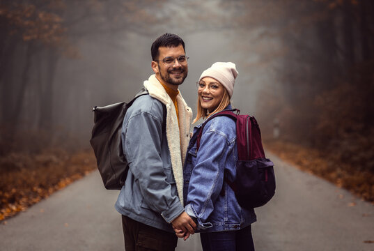 Portrait of couple spending time together walking on forest road on a foggy morning.