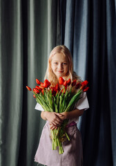 little girl with bunch of red tulips