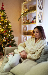 Alone sad woman don't like Christmas time, tired and unhappy at decorated festive living room
