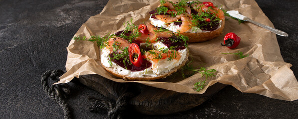 bagels with cream cheese, salmon and beets on a dark table