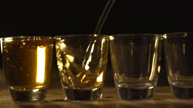 Closeup slowmotion shot of shots being poured into shot glasses on a bar