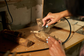 Female using power wood working tools graver, carving while crafting