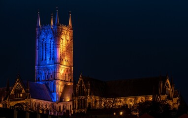 View of Lincoln Cathedral illuminated with blue and yellow lights. England, United Kingdom.