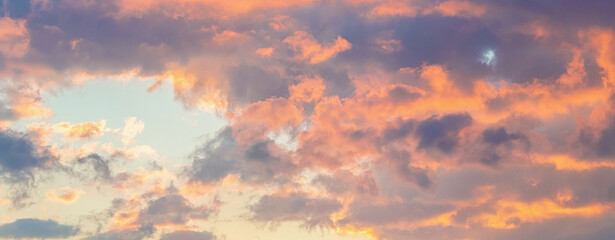 Dramatic cumulus clouds on sunny day at sunset painted with sun, with some birds flying. Banner. Atmosphere multicolor background or wallpaper