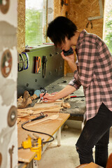 Cheerful carpenter woman discussing order details with her customer on smartphone